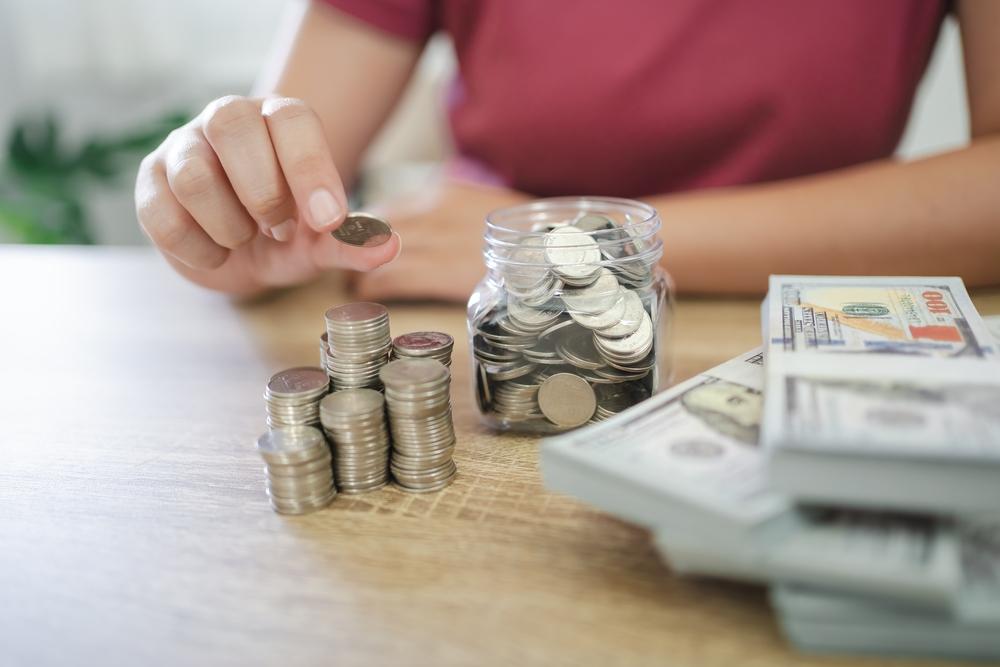 Persona recopilando monedas y billetes sobre una mesa