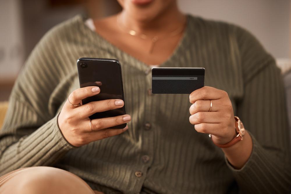 Persona sosteniendo una tarjeta en una mano y un celular en la otra