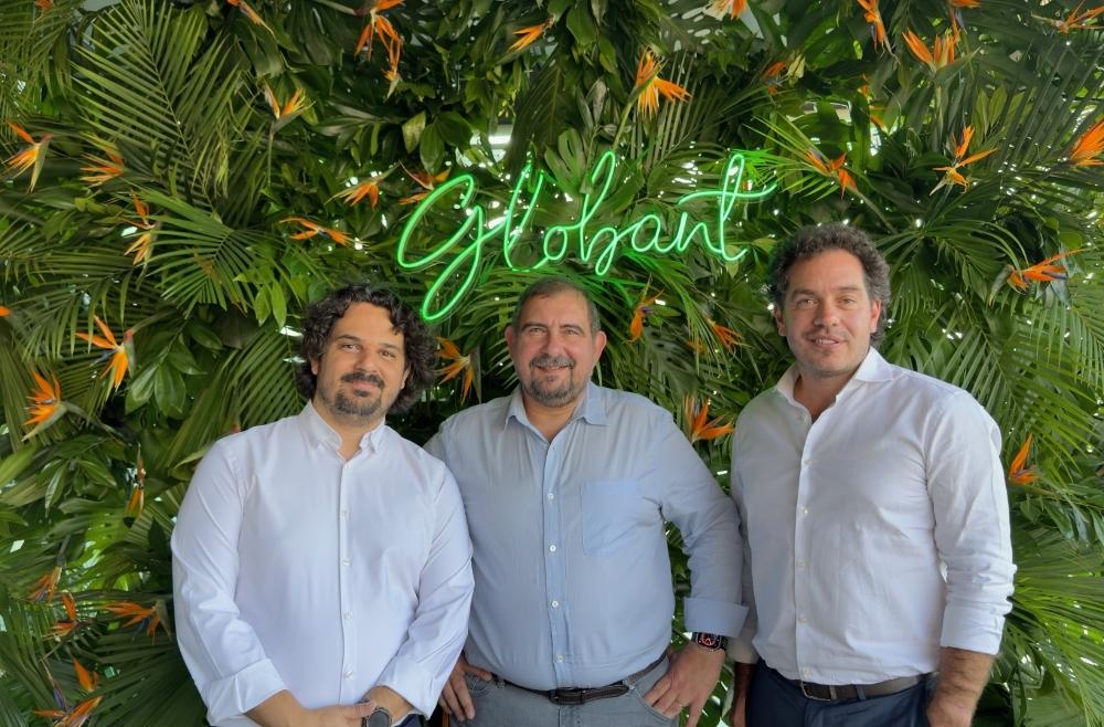 Tres personas con camiseta azul posando ara la cámara con un fondo verde