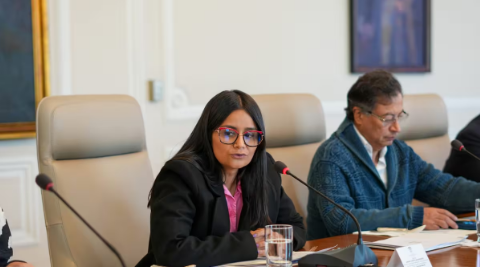 Foto de una mujer con sentada con un micrófono al frente