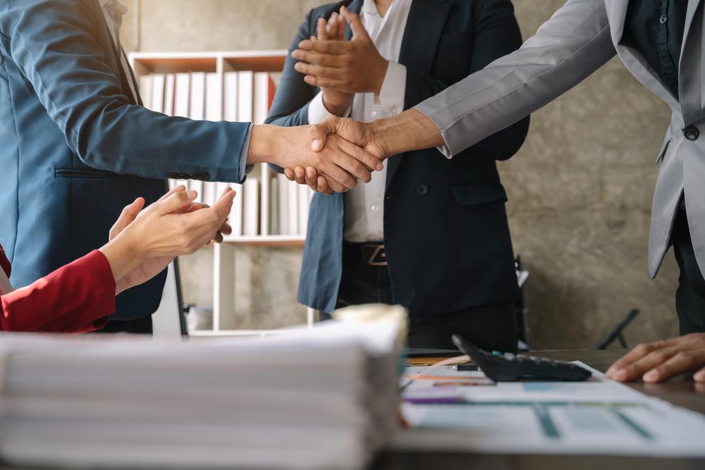 Foto de dos personas dándose la mano sobre una mesa