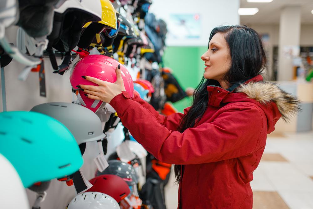 Una mujer con chaqueta roja toma un casco  rosado de un local 