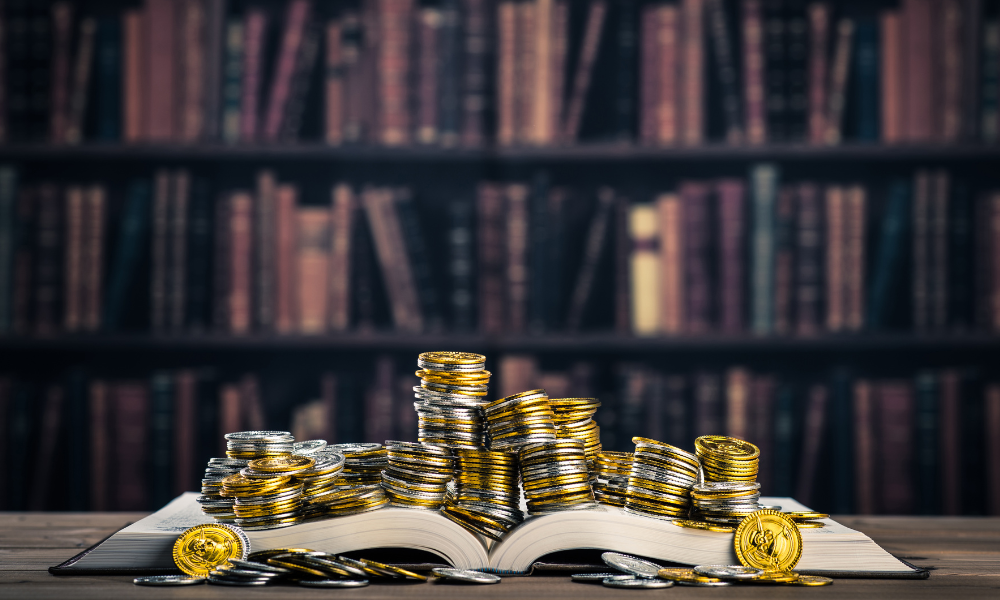 Libro abierto con monedas encima haciendo alusión a los libros de finanzas e inversiones