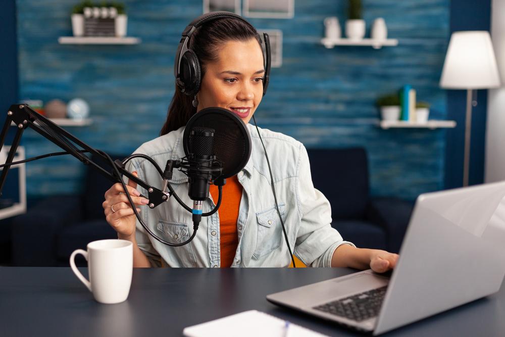 Foto de mujer hablando por micrófono al frente de un computador